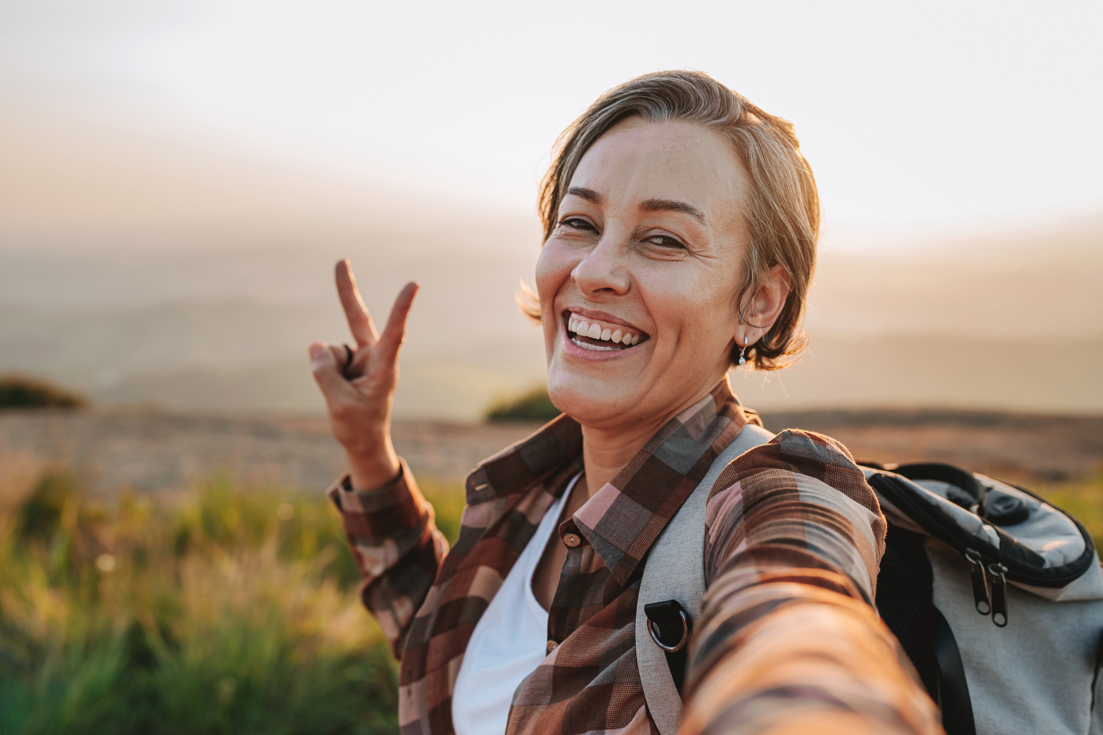 Woman hiking, smiling and giving a peace sign